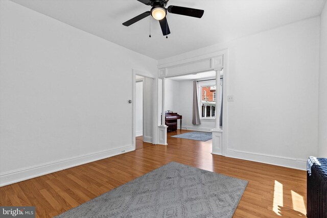 unfurnished room featuring baseboards, radiator, ceiling fan, and wood finished floors