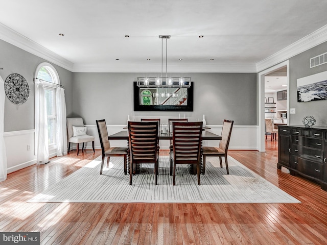 dining area featuring wood-type flooring, crown molding, and baseboards