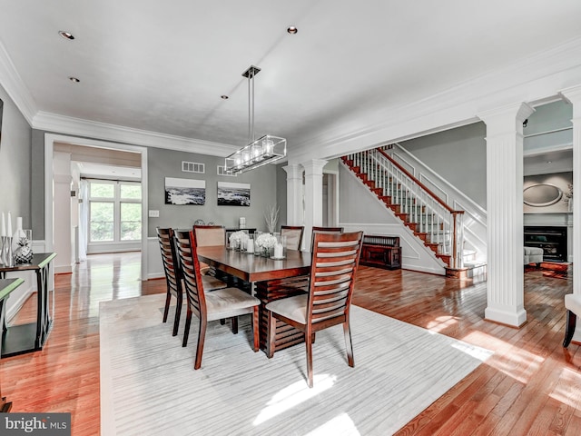 dining space with decorative columns, stairs, light wood finished floors, crown molding, and baseboards