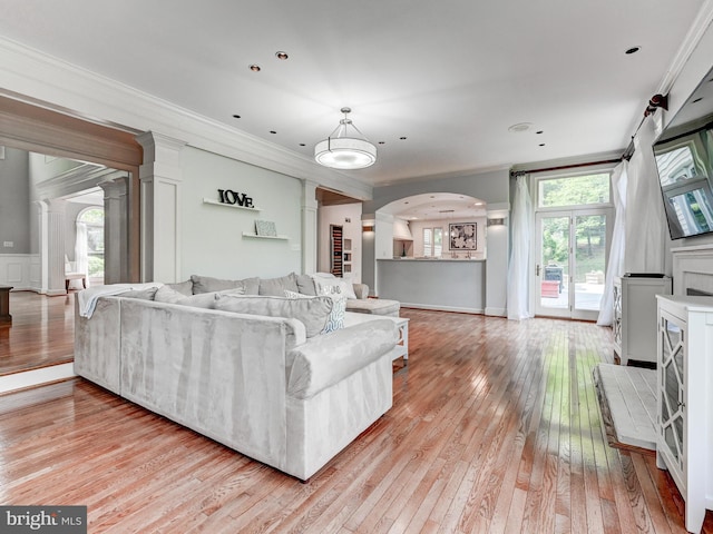 living area with ornate columns, ornamental molding, light wood-type flooring, and healthy amount of natural light