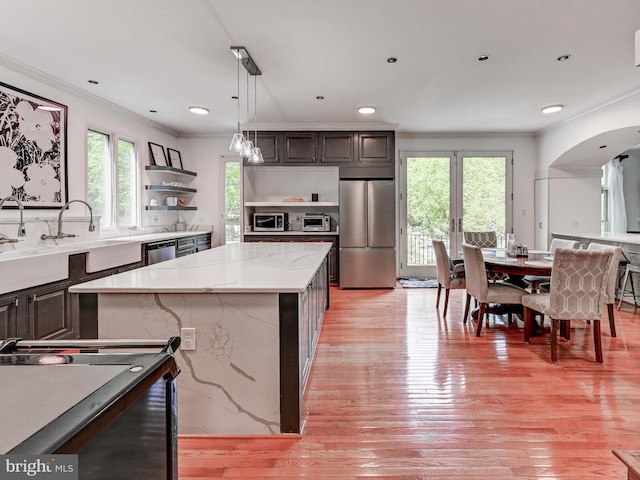 kitchen featuring stainless steel appliances, open shelves, crown molding, healthy amount of natural light, and arched walkways