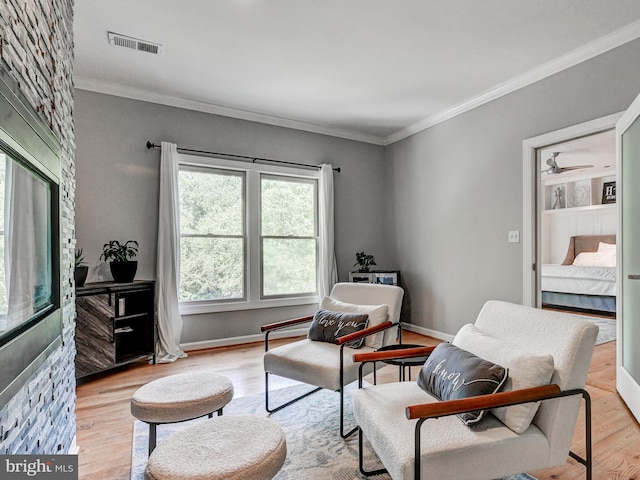 sitting room featuring ornamental molding, light wood-type flooring, and baseboards