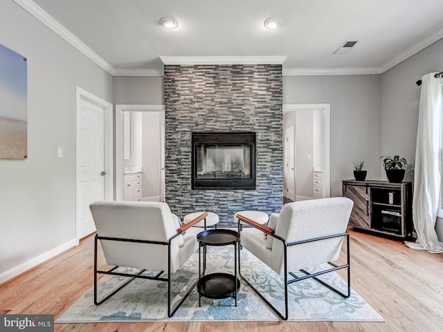 living room with wood finished floors, a tile fireplace, crown molding, and baseboards