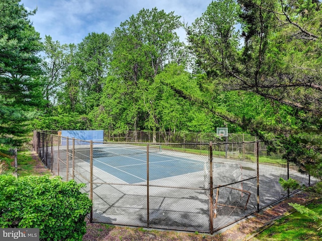 view of sport court featuring a tennis court and fence