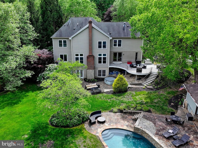 back of property with a patio area, a yard, an outdoor pool, stairs, and a deck