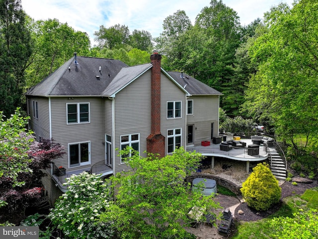 rear view of house featuring a deck, a chimney, and stairway