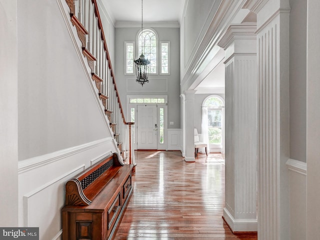 foyer entrance featuring hardwood / wood-style floors, stairway, a towering ceiling, and ornamental molding