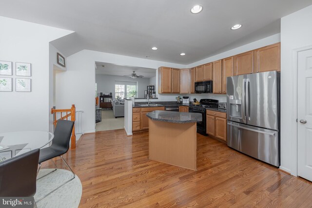 kitchen with recessed lighting, a sink, light wood finished floors, and black appliances