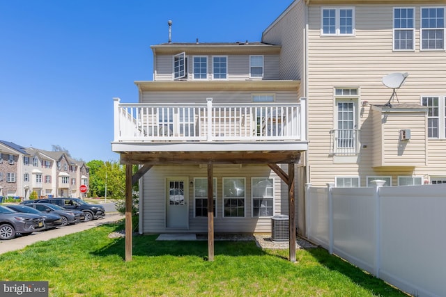 rear view of house featuring a lawn, fence, a wooden deck, and uncovered parking