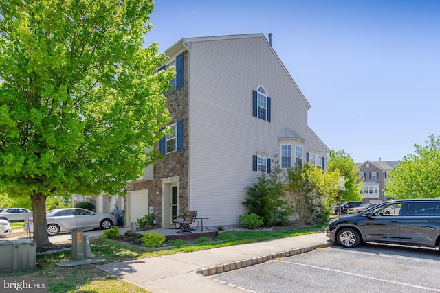 view of home's exterior featuring uncovered parking and stone siding