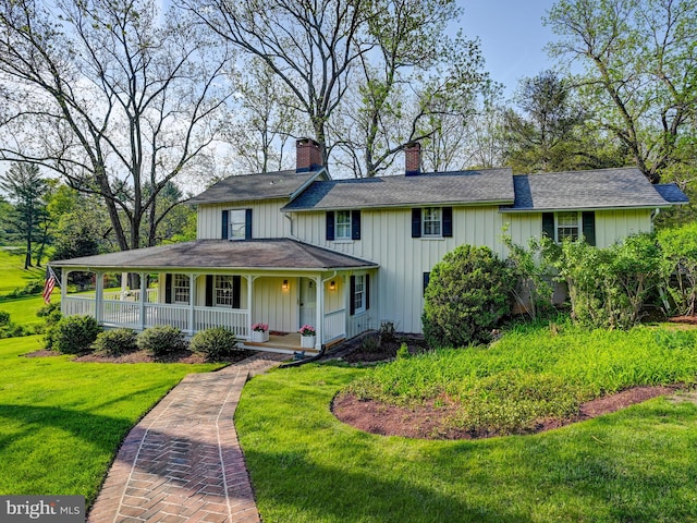 farmhouse inspired home with a porch, a chimney, a front lawn, and board and batten siding