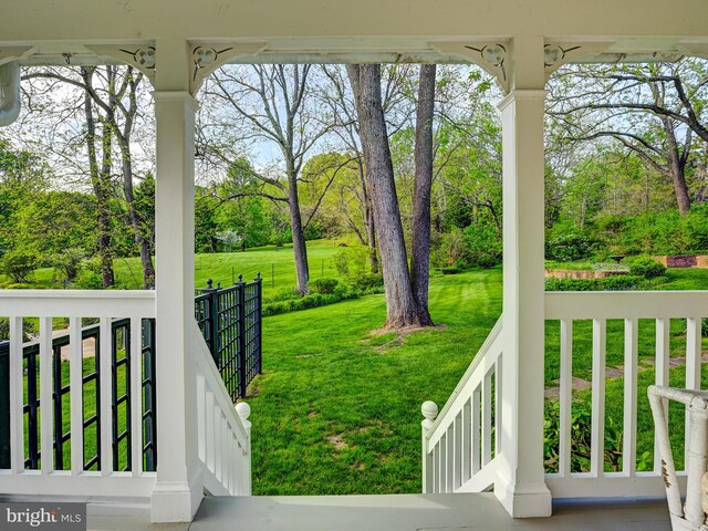 view of green lawn featuring covered porch and view of scattered trees
