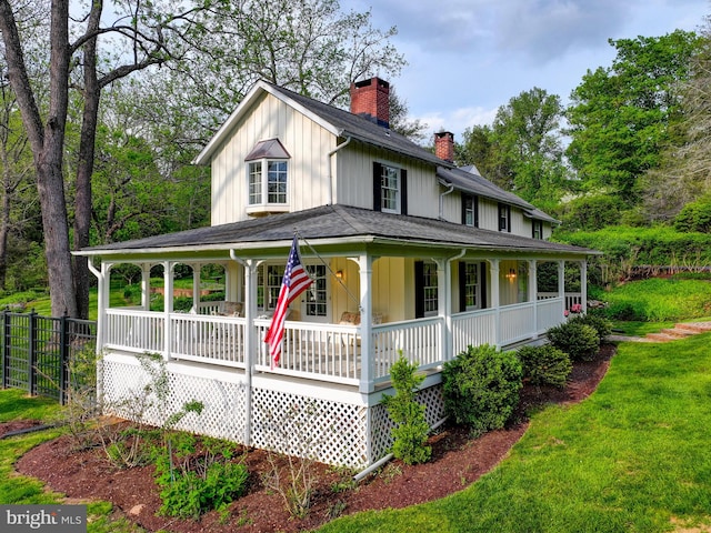 country-style home with covered porch, a chimney, fence, and a shingled roof