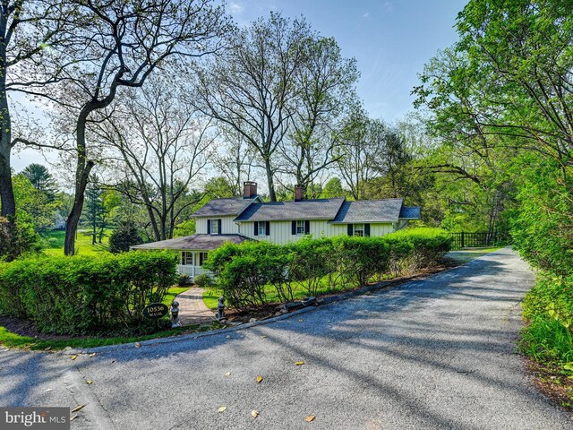 view of front of home featuring a chimney, driveway, and fence