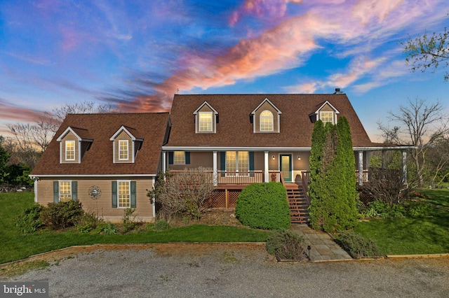 cape cod house featuring a porch, roof with shingles, and stairway
