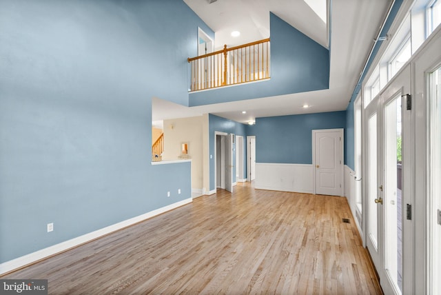 unfurnished living room with stairs, a high ceiling, and wood finished floors