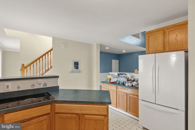 kitchen with dark countertops, freestanding refrigerator, a peninsula, and visible vents