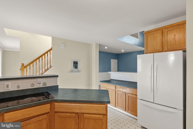 kitchen with visible vents, freestanding refrigerator, a peninsula, and dark countertops