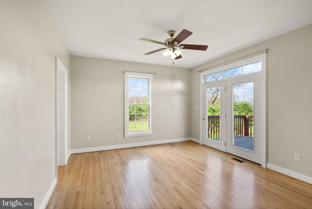 empty room with baseboards, plenty of natural light, a ceiling fan, and wood finished floors