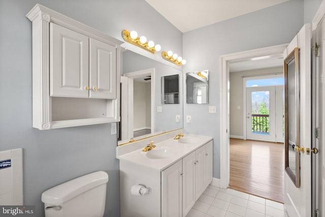 bathroom with tile patterned flooring, a sink, double vanity, and toilet