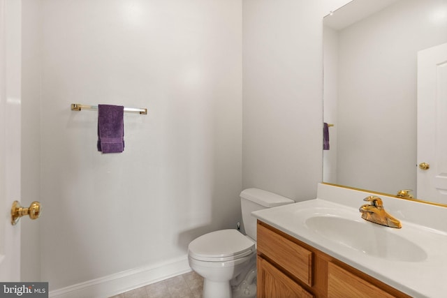 half bathroom featuring baseboards, toilet, and vanity