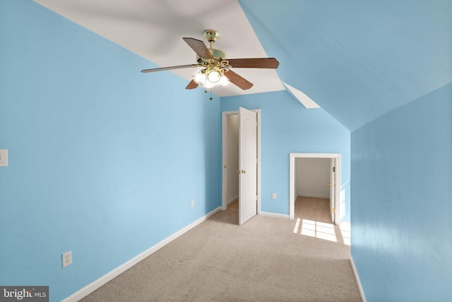 interior space featuring baseboards, a ceiling fan, lofted ceiling, and light carpet