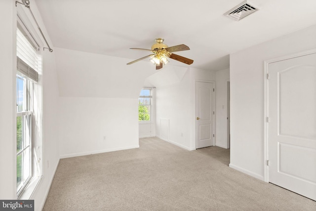 interior space with ceiling fan, visible vents, baseboards, lofted ceiling, and carpet