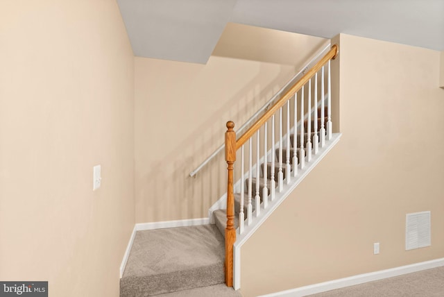 staircase with carpet floors, baseboards, and visible vents