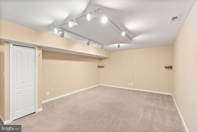 finished basement with visible vents, carpet flooring, baseboards, and rail lighting