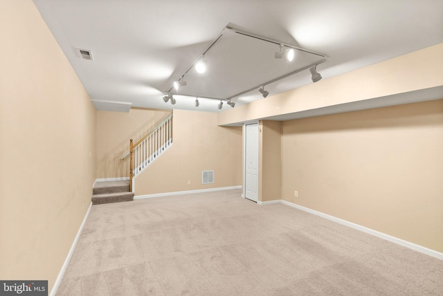 finished below grade area with carpet floors, baseboards, visible vents, and stairway