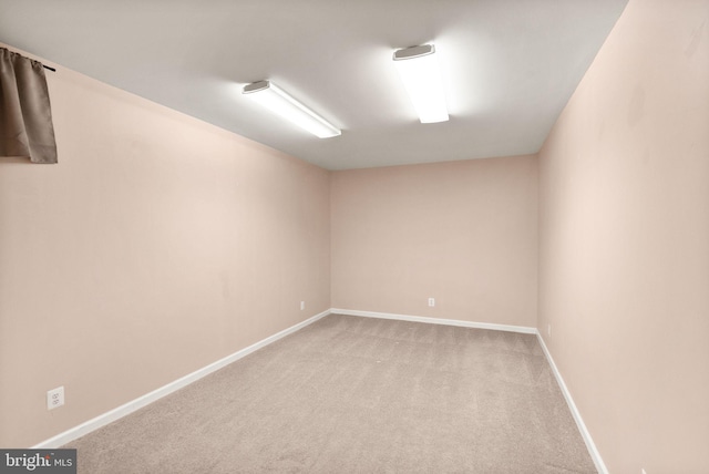 empty room featuring baseboards and light colored carpet