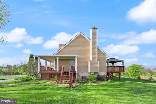 back of property with a lawn, a wooden deck, a chimney, a gazebo, and stairway