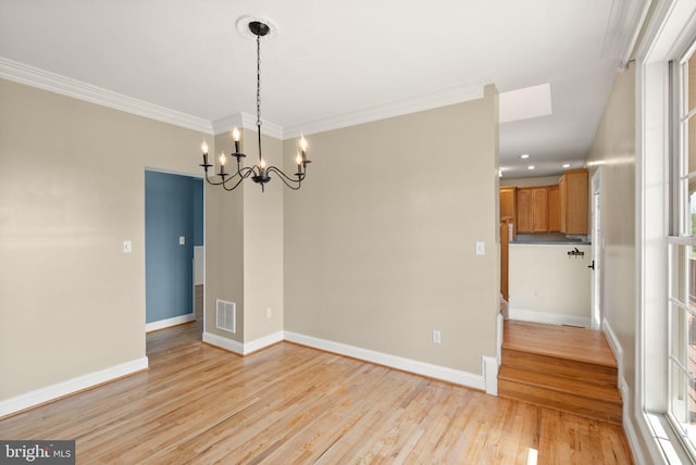 unfurnished dining area featuring visible vents, crown molding, baseboards, light wood-type flooring, and a notable chandelier
