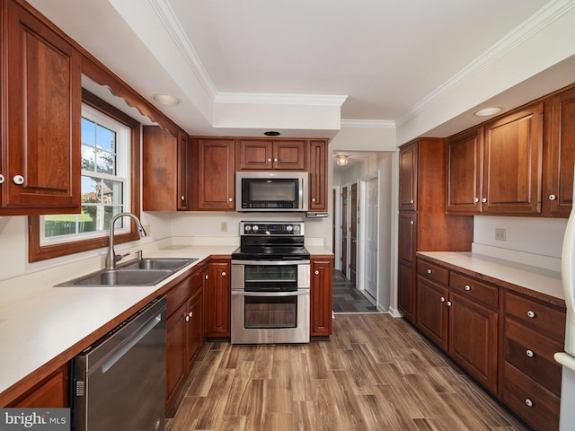 kitchen featuring dark wood finished floors, a sink, light countertops, ornamental molding, and stainless steel appliances