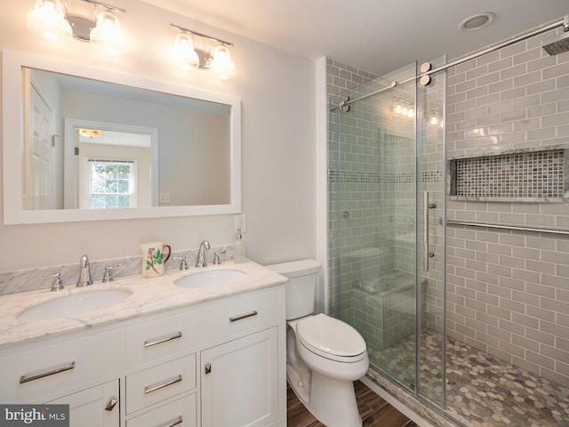 full bathroom featuring wood finished floors, a sink, a stall shower, and toilet