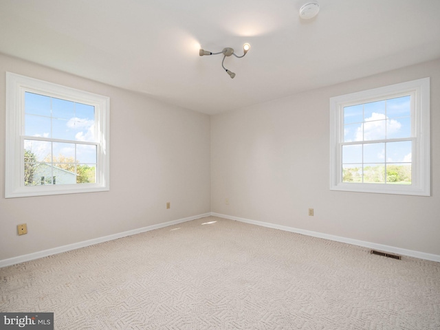 unfurnished room featuring visible vents, baseboards, and plenty of natural light