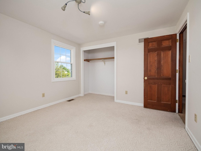 unfurnished bedroom with light colored carpet, baseboards, visible vents, and a closet