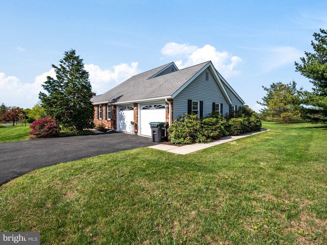 view of side of home with a lawn, an attached garage, driveway, and brick siding