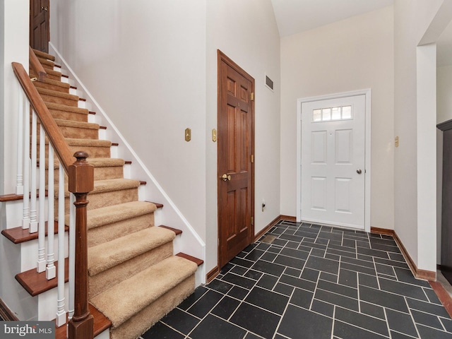 foyer entrance with visible vents, stairs, and baseboards