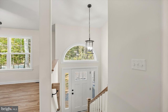 foyer featuring baseboards, a chandelier, and wood finished floors
