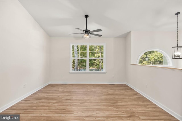 unfurnished room with baseboards, light wood finished floors, and ceiling fan with notable chandelier