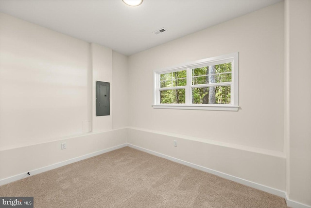 carpeted spare room featuring baseboards, electric panel, and visible vents