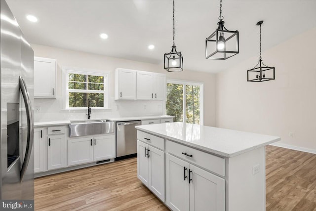 kitchen with a sink, a healthy amount of sunlight, a kitchen island, and stainless steel appliances