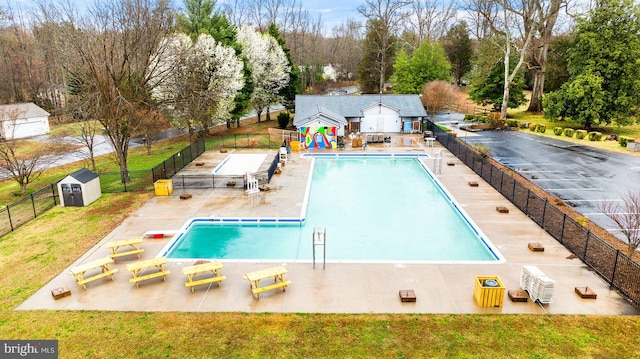 pool featuring a patio, a yard, fence, and an outbuilding
