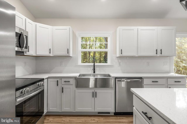 kitchen featuring a sink, light wood-style flooring, appliances with stainless steel finishes, and tasteful backsplash