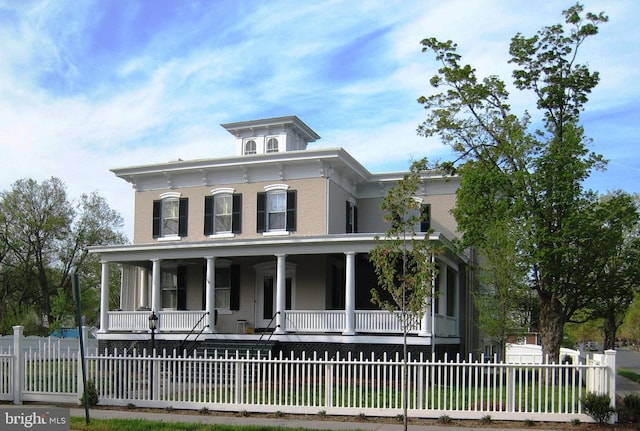 italianate home with a porch and a fenced front yard
