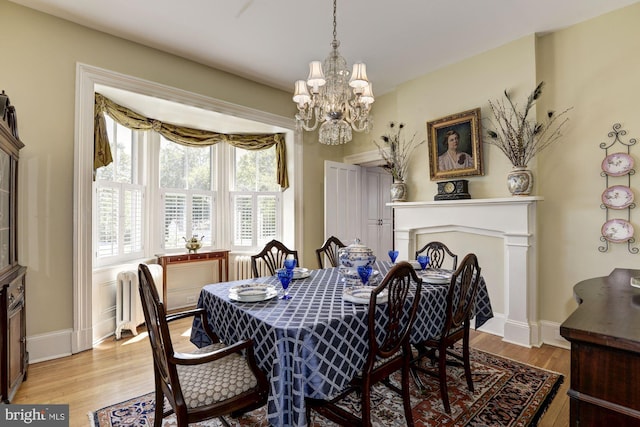 dining room featuring baseboards, a chandelier, radiator, and light wood-style floors