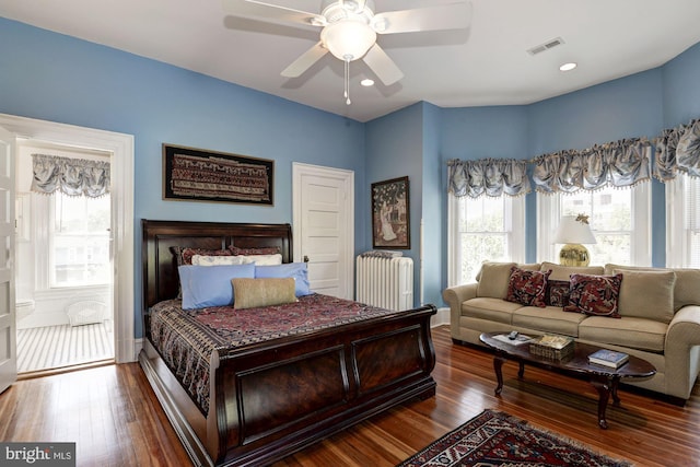 bedroom featuring visible vents, baseboards, radiator, and wood finished floors