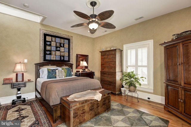bedroom with ceiling fan, baseboards, visible vents, and wood finished floors
