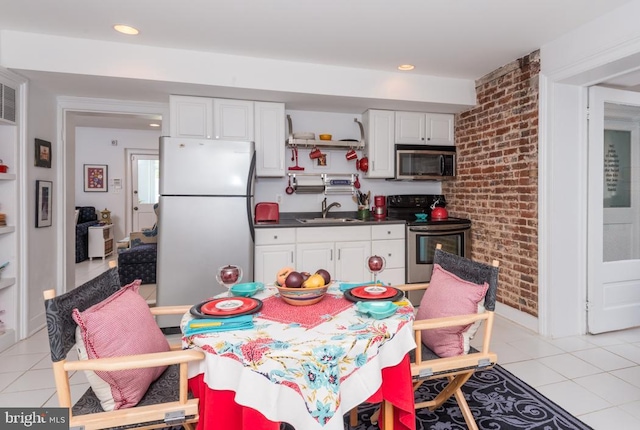 kitchen with a sink, appliances with stainless steel finishes, light tile patterned floors, and dark countertops